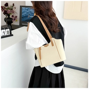 Close-up of cream white lychee pattern tote bag with brown leather handles and brand tag