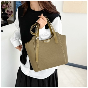 Detail of olive green leather tote bag with dual handles and adjustable shoulder strap
