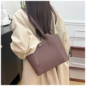 Detail view of the deep brown large capacity tote bag worn on shoulder by a model