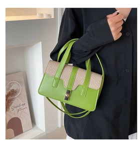 Close-up of beige woven texture and green leather contrast paneling on the handbag
