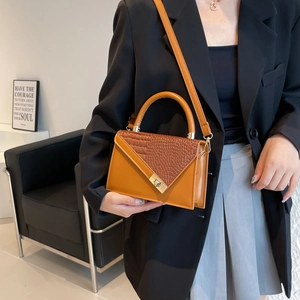 Brown vintage handbag with crocodile texture flap and gold twist lock in lifestyle view