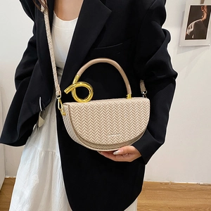 Sacoche beige en cuir tressé avec poignée dorée et bandoulière large portée par mannequin