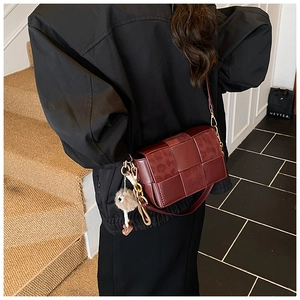 Detailed view of woven red leather shoulder bag with leopard print flap on model