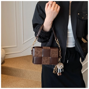 Detail of woven leather and leopard print handbag with golden chain and fuzzy charm