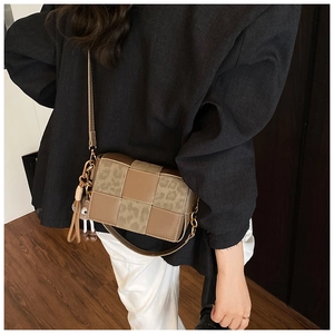 Close-up of a brown woven square bag with leopard print details and a tassel charm