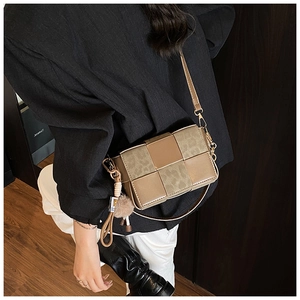 Detail of a vintage woven crossbody bag featuring textured panels and a decorative pompom