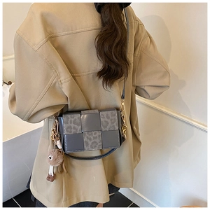 Detail of vintage woven crossbody bag with leopard print patches and plush charm