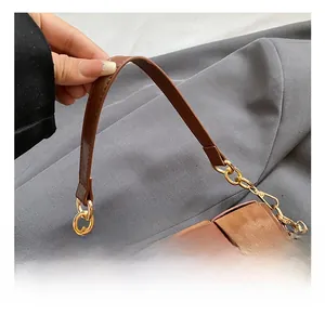 Close-up of woven brown leather handbag with gold metal hardware and smooth handle