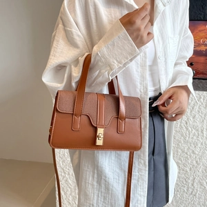 Brown leather handbag with woven texture detail and gold twist lock shown on model