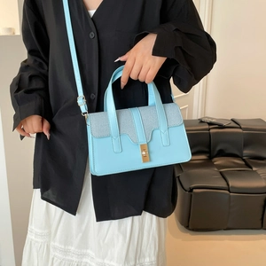 Light blue faux leather handbag with gold clasp shown on a model in a modern setting