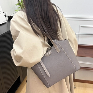 Chic taupe canvas tote bag with leather trim worn by model in a modern office setting