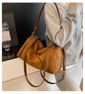 Vue latérale d'un grand sac cabas en daim marron avec bandoulières en cuir porté par un modèle