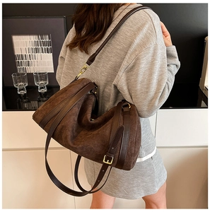 Détail du grand cabas en daim marron foncé avec finitions en cuir lisse et boucles dorées
