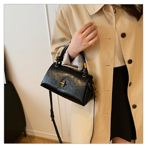 Chic black textured leather crossbody bag with gold twist lock shown on a model