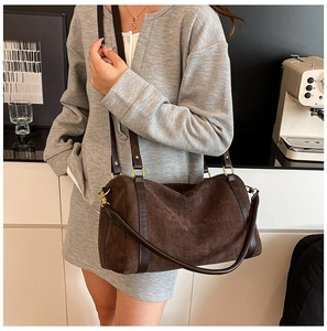 Détail du sac Boston en daim marron foncé mat avec lanières en cuir et boucles dorées