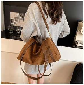 Détail de la bandoulière réglable en cuir et boucle sur un sac cabas en daim marron