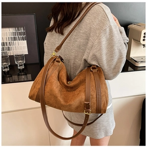 Détail d'un grand cabas en daim marron avec lanières en cuir et boucles dorées