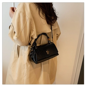 Detail of a black leather handbag with a knotted handle and gold metal twist-lock buckle