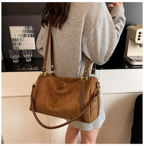 Détail du sac seau en daim marron avec boucles en métal doré sur la bandoulière cuir