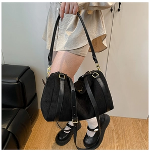 Détail macro d'un sac cabas en daim noir avec boucles dorées et renforts en cuir
