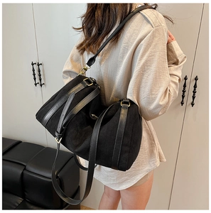 Détail du sac cabas en daim noir mat avec bandoulières en cuir lisse et boucles dorées