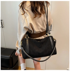 Détail du grand sac cabas noir en daim porté à l'épaule par un mannequin en extérieur
