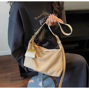 Detail of beige suede hobo bag with slim leather strap and mini charm pendant