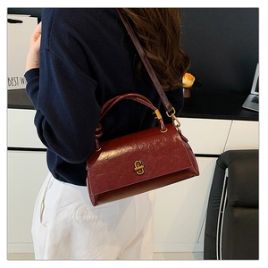Detail of dark red leather handbag with gold rotating lock and chic shoulder strap style