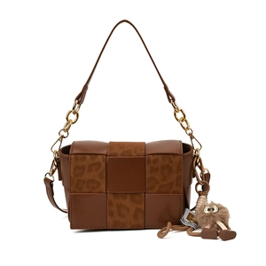 Brown woven leather handbag with leopard print flap, gold chain strap and plush charm