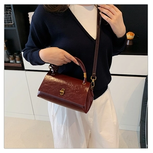 Detailed view of wine red patent leather handbag with vintage gold metallic buckle clasp