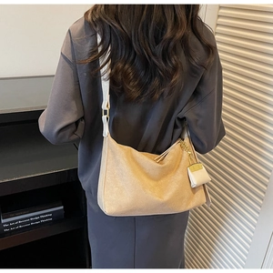 Detail of khaki suede hobo bag featuring gold adjustment buckle and mini tassel charm