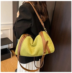 Détail du grand sac cabas en daim vert avec lanières en cuir marron porté par un mannequin