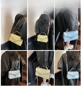 Modèle présentant des sacs à main carrés bicolores en daim jaune et bleu tendance