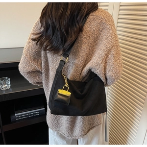 Detail view of a black suede hobo bag with gold hardware and a mini chain charm
