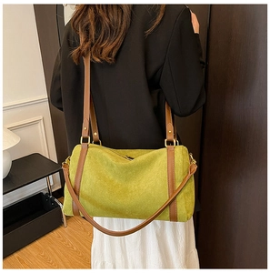 Détail du sac cabas en daim vert herbe avec bandoulière en cuir brun porté par un modèle