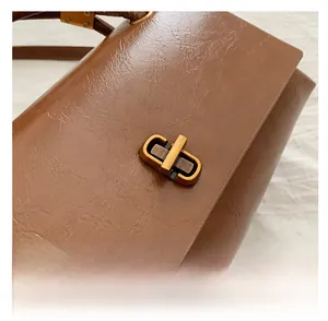 Close-up of vintage brown PU leather texture and antique gold metal twist lock on a handbag
