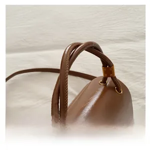 Detail view of the brown glossy leather handle with gold vintage metal buckles
