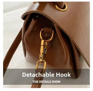 Macro shot of detachable gold hooks and brown leather strap on minimalist handbag