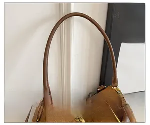 Détails des fines bandoulières et du zip en métal doré sur le sac cabas en daim marron