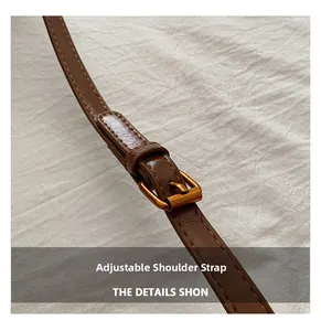 Close-up of adjustable brown leather shoulder strap with vintage bronze buckle