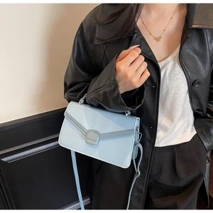 Détail du sac bandoulière bleu clair avec rabat en V et look veste en cuir