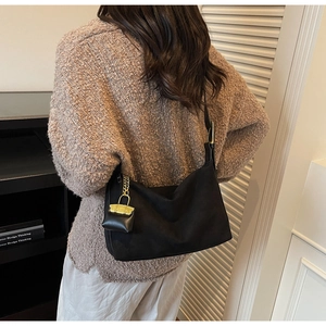 Detail of black suede tote bag featuring a chic golden chain mini pouch charm accessory