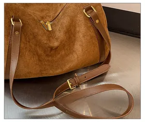 Vue détaillée du sac en daim marron avec bandoulière en cuir réglable et boucle dorée