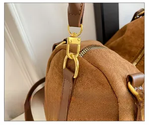 Vue macro de la quincaillerie dorée et du zip sur le sac fourre-tout en daim marron