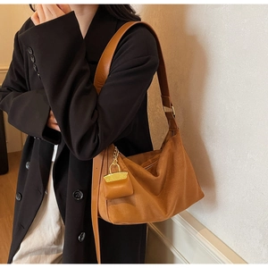Detail of brown faux suede hobo bag with wide leather strap worn with black blazer
