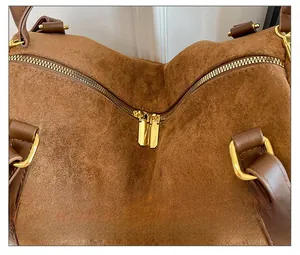 Détail d'un sac cabas en daim marron avec doubles fermetures éclair dorées et anneaux en D