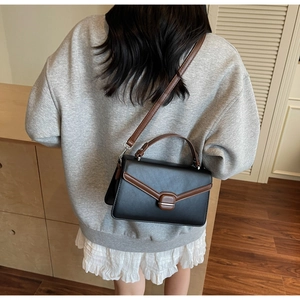 Détail du sac bandoulière noir et marron classique avec boucle en métal et bordure en cuir