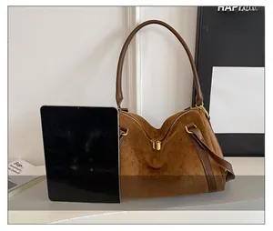 Comparaison de taille du cabas en daim marron avec une tablette montrant sa grande capacité