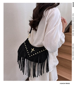 Detail of black suede fringe crossbody bag with gold rivet studs and cross ornament