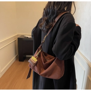 Detail of caramel suede tote bag with decorative mini pouch and golden chain strap
